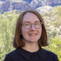 A headshot of a person smiling against a green background.